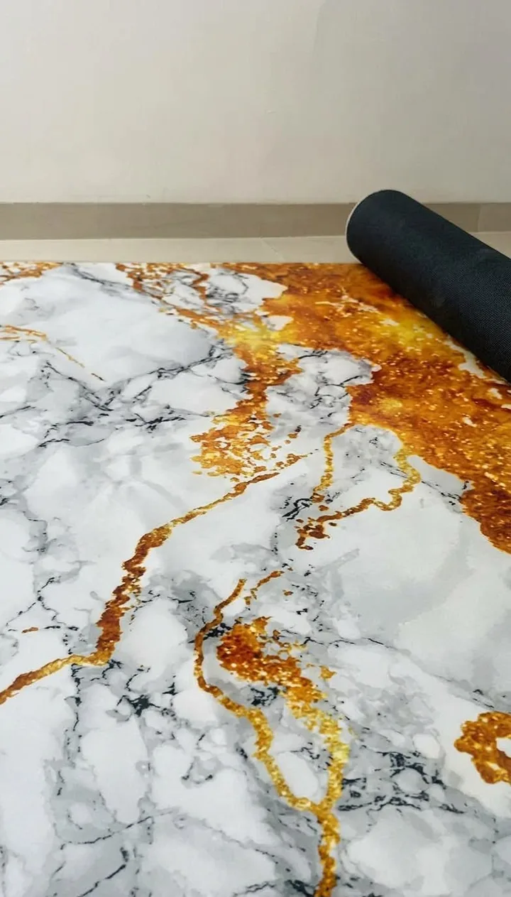 Foto de un cliente desenrollando su tapete Ónix Dorado en casa